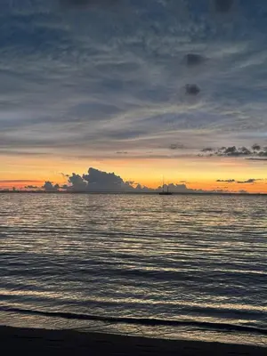 a sunset over the water with a boat in the distance at Coco Calm Title Halo 1 in Koh Lone