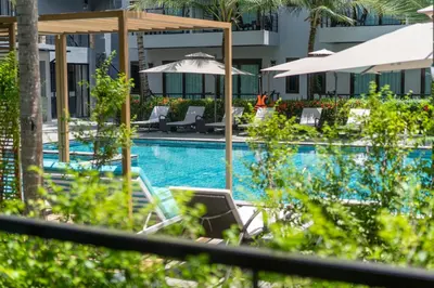a pool with chairs and umbrellas and a laptop at Howard Johnson by Wyndham Phuket Naiyang in Thalang