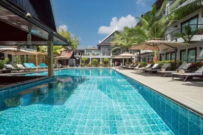 a swimming pool with chairs and umbrellas at a hotel at Howard Johnson by Wyndham Phuket Naiyang in Thalang