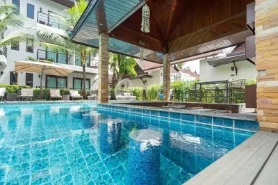 a swimming pool with an umbrella and a building at Howard Johnson by Wyndham Phuket Naiyang in Thalang