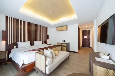 a bedroom with a bed and a couch and a tv at Howard Johnson by Wyndham Phuket Naiyang in Thalang