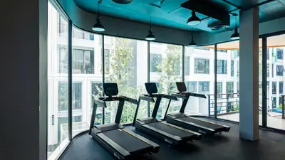 a row of treadmills in a gym with windows at Apartment studio in Bellevue Lagoon on Bang Tao in Laguna Phuket