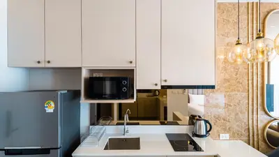 a kitchen with white cabinets and a sink and a refrigerator at Apartment studio in Bellevue Lagoon on Bang Tao in Laguna Phuket