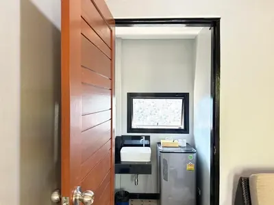 a bathroom with a wooden door and a sink at Saiinam Laguna Inn in Ban Thalat Choeng Thale