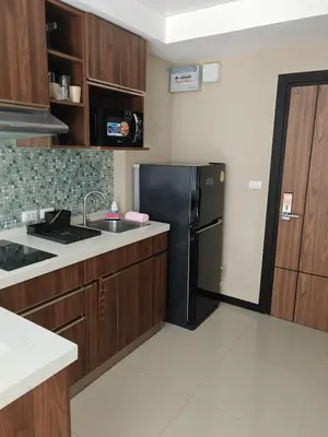 a kitchen with a black refrigerator and wooden cabinets at One-bedroom condo on Nai Harn Beach, Rawai in Rawai Beach