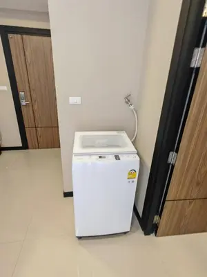 a small white refrigerator in a room with a door at One-bedroom condo on Nai Harn Beach, Rawai in Rawai Beach