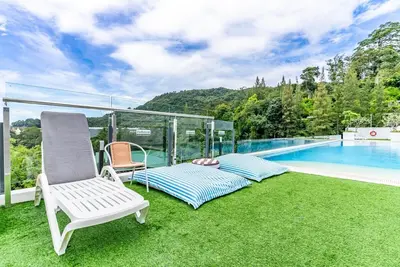 a patio with a white chair and a swimming pool at Fantasea by Villacarte in Kamala Beach