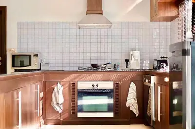 a kitchen with wooden cabinets and an oven at MYSA House Pool Villa Central Phuket in Phuket