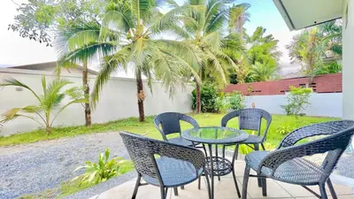 a patio with a table and chairs and palm trees at MYSA House Pool Villa Central Phuket in Phuket
