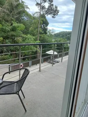 a chair on a balcony with a view of trees at Kamala falls seaview 1 bedroom in Phuket Town