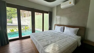 a bedroom with a bed and a large window at Villa avec piscine privée in Kamala Beach