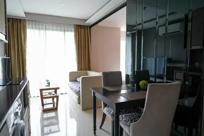 a living room with a table and chairs in a room at 1 bedroom Mida Grande Resort, Phuket in Surin Beach