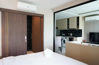 a bedroom with a white bed and a kitchen at 1 bedroom Mida Grande Resort, Phuket in Surin Beach