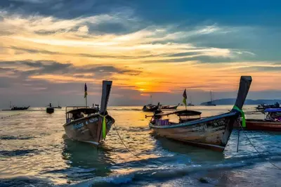 a group of boats sitting in the water at sunset at XX GO INN Aonang Beach - หาดอ่าวนาง กระบี่ in Ban Khlong Haeng