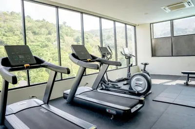 a gym with two exercise bikes in a room with windows at Utopia Karon - Karon Beach in Karon Beach