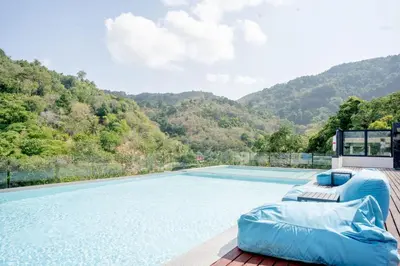 a swimming pool with a blue couch next to a mountain at Utopia Karon - Karon Beach in Karon Beach