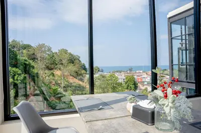a living room with a table and a large window at Utopia Karon - Karon Beach in Karon Beach