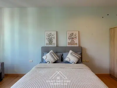 a bedroom with a bed with two paintings on the wall at THe bell chalong phuket 19 in Ban Klang