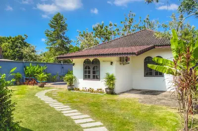 a small white house with a grass yard at Serenity Holiday Pool Villa, Bangtao Beach in Surin Beach