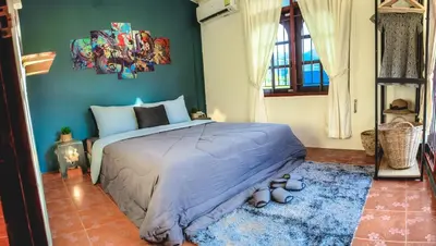 a bedroom with a large bed with a blue wall at Serenity Holiday Pool Villa, Bangtao Beach in Surin Beach