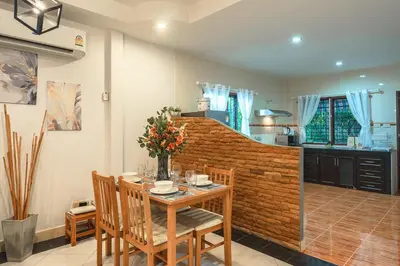 a dining room with a table and chairs and a kitchen at Coastline Pearl Holiday Home, Bangtao Beach in Ban Thalat Choeng Thale