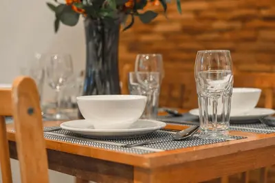 a table with plates and glasses and a vase at Coastline Pearl Holiday Home, Bangtao Beach in Ban Thalat Choeng Thale