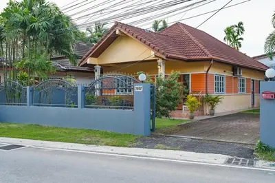 a house with a blue fence in front of it at Areca Holiday Home 1, Bangtao Beach in Ban Thalat Choeng Thale