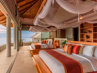 two beds in a bedroom with a view of the ocean at Baan Paa Talee Estate - SHA Extra Plus in Kamala Beach