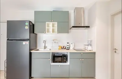 a kitchen with blue cabinets and a refrigerator at The Title Halo1 350 m to NaiYang Brand-New 1BR in Nai Yang Beach