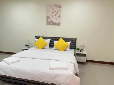 a bedroom with a large white bed with yellow pillows at Muttafa House in Nai Yang Beach