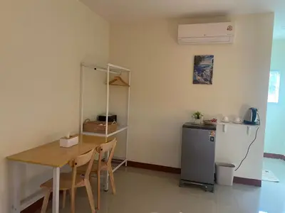 a dining room with a table and a refrigerator at Muttafa House in Nai Yang Beach