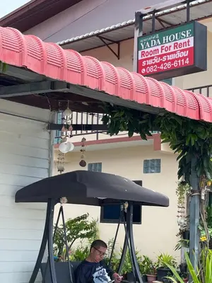 a man sitting in a chair under an umbrella at Yada House Sunny Place in Ban Bo Han