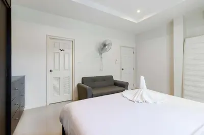 a white bedroom with a bed and a chair at C230 Chill 1BR Sea View, Near Beach & Muay Thai in Rawai Beach