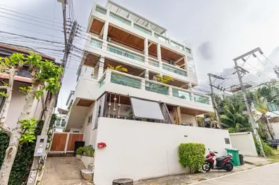 a white house with a scooter parked in front of it at C230 Chill 1BR Sea View, Near Beach & Muay Thai in Rawai Beach