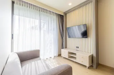 a living room with a couch and a tv on a wall at C228 Brand New Condo Near Beach & Prime Location in Bang Tao Beach