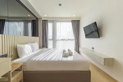 a bedroom with a bed and a tv on a wall at C228 Brand New Condo Near Beach & Prime Location in Bang Tao Beach