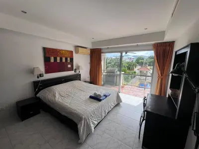a bedroom with a bed and a window with a view at Rawai Condominium in Ban Saiyuan (1)