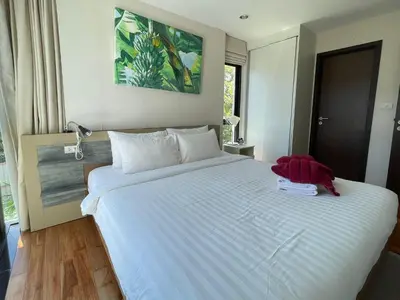 a bedroom with a large white bed with a red shirt on it at The Title Rawai Aparthotel by HSS in Rawai Beach