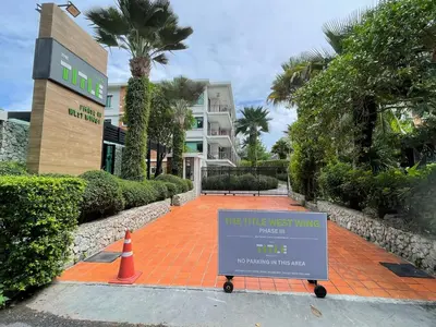 a sign on a sidewalk in front of a building at The Title Rawai Aparthotel by HSS in Rawai Beach