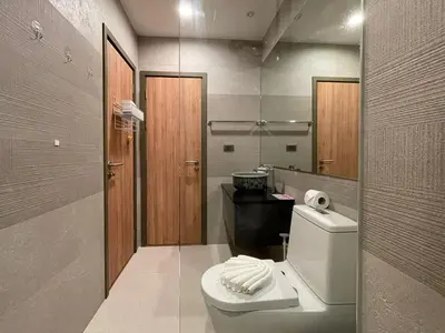 a bathroom with a toilet and a sink and a mirror at The Title Rawai Aparthotel by HSS in Rawai Beach