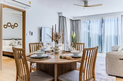 a dining room with a wooden table and chairs at Beachside 1 BR apartment by NLA in Bang Tao Beach