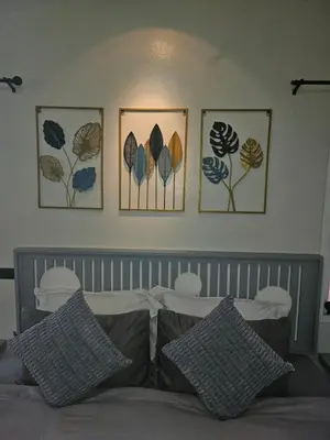 four pictures on the wall above a bed with pillows at Tropical Hideaway Close to the Beach in Ban Thalat Choeng Thale