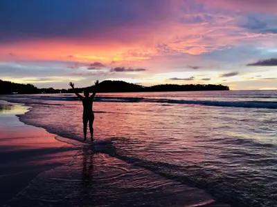 a person standing on a beach with their arms in the air at Tropical Hideaway Close to the Beach in Ban Thalat Choeng Thale