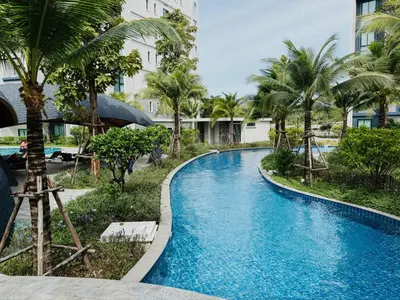 a swimming pool with palm trees and a building at FAMILY HOMES - Brand New 2BDRM Poolside Apartment in Phuket