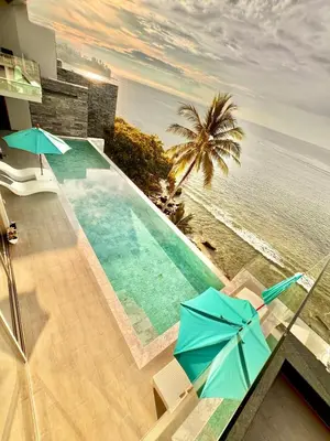 a swimming pool with chairs and umbrellas next to the ocean at Kamala Beach Front Sea View 6 Bedroom Villa in Kamala Beach