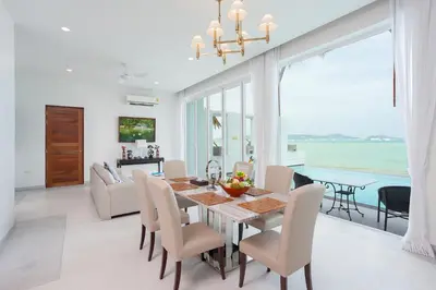 a dining room with a table and chairs and the ocean at Fisherman Way Beach Villa in Rawai Beach