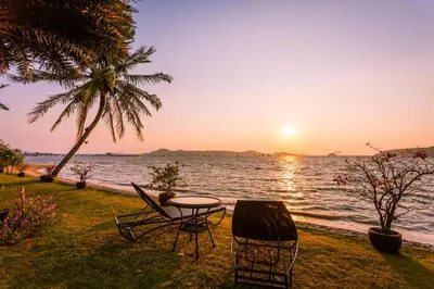 a table and chairs next to the ocean at sunset at Fisherman Way Beach Villa in Rawai Beach