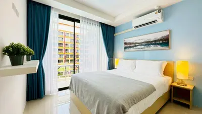 a bedroom with a bed with blue walls and a window at Cozy condo maikhao Phuket in Ban Mai Salae