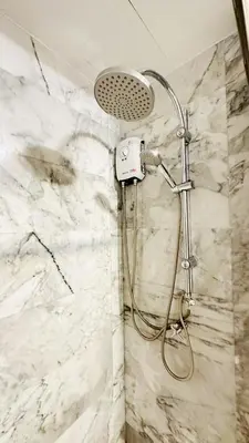 a shower in a bathroom with a white marble wall at Cozy condo maikhao Phuket in Ban Mai Salae
