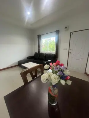 a living room with a table with a vase of flowers at Ann & John Guesthouse in Patong Beach
